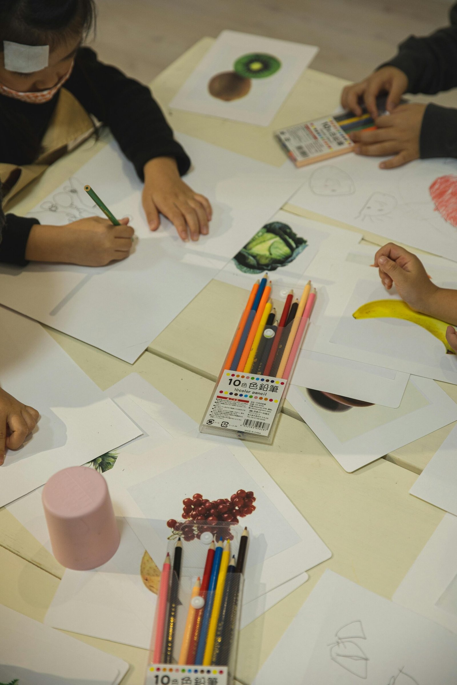Kids drawing with colored pencils at a table, enhancing creativity and education indoors.